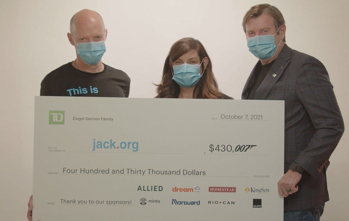 Three people holding a large check with faces on it.